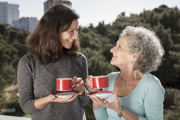 Portrait of happy senior mother and her daughter drinking tea